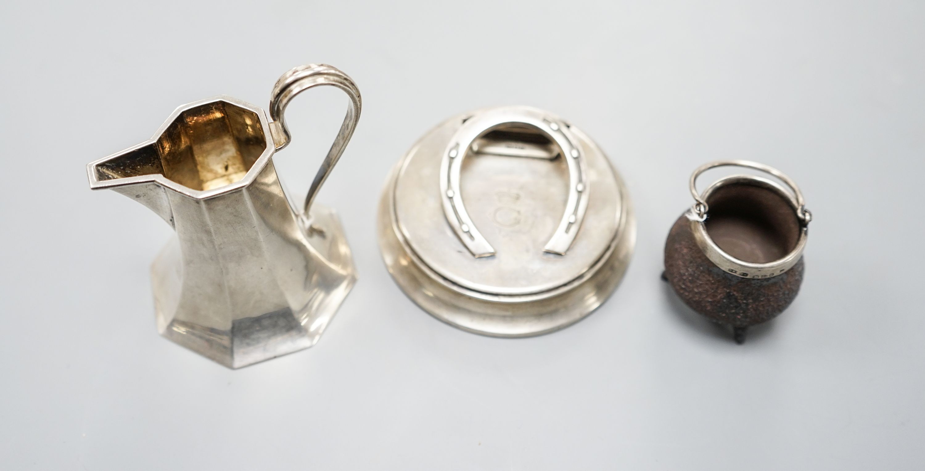 An Edwardian silver horseshoe letter clip, London, 1907, 86mm, a silver cream jug and a silver mounted Doulton Lambeth stoneware miniature cauldron.